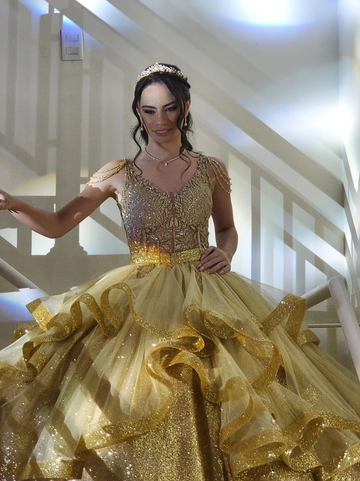 Debutante em vestido dourado descendo a escada no Espaço Santa Rosa