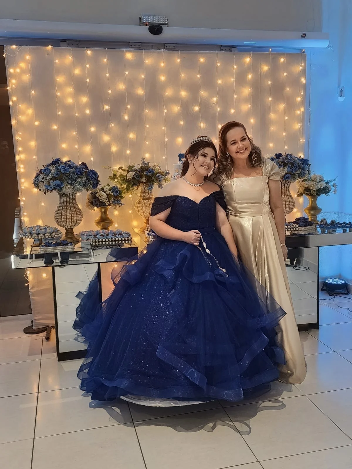 Debutante e acompanhante em frente à decoração de luzes do Espaço Santa Rosa